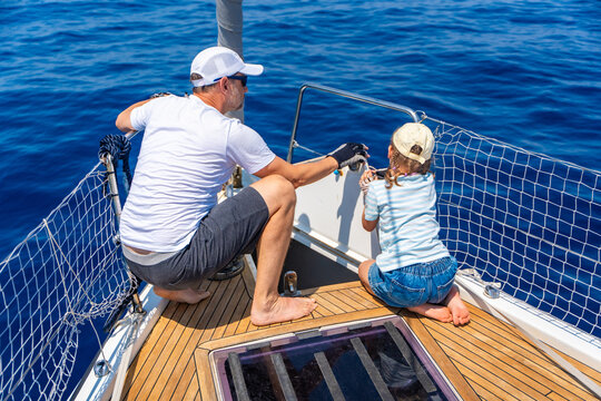 Father teaching his daughter basic yacht maintenance during a family sailing trip. Learning practical sailing skills, teamwork and confidence through shared outdoor experience.