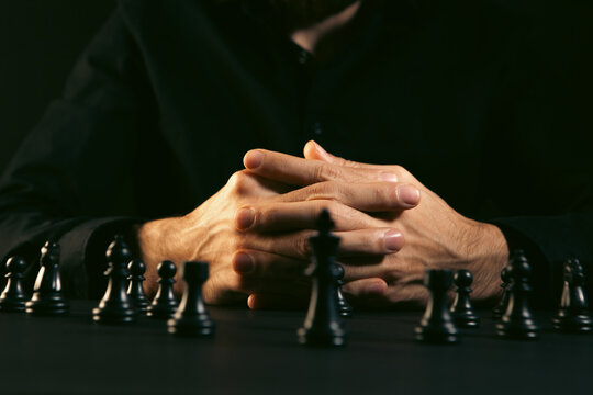 Close up of a man playing chess on a dark background with copy space