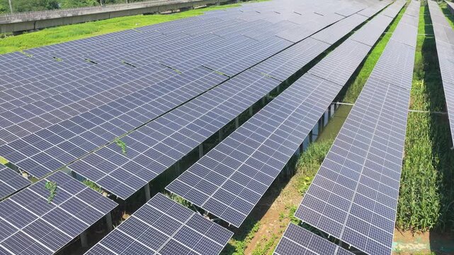 Drone flying forward between long rows of solar panels