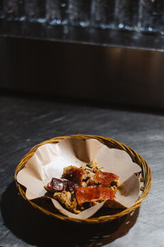 Authentic Balinese babi guling roasted pork dish served in a traditional woven plate under moody lighting