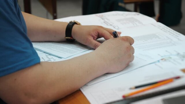 Close-up of engineer reviewing and writing on technical documents, drawings and data sheets at a desk. Engineering documentation, planning and project work.