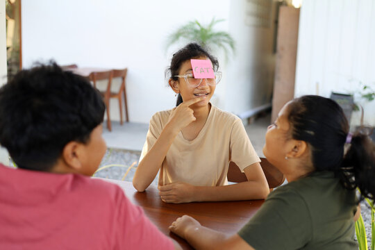 Children play the guessing game "Who am I?", with paper stickers on their foreheads.