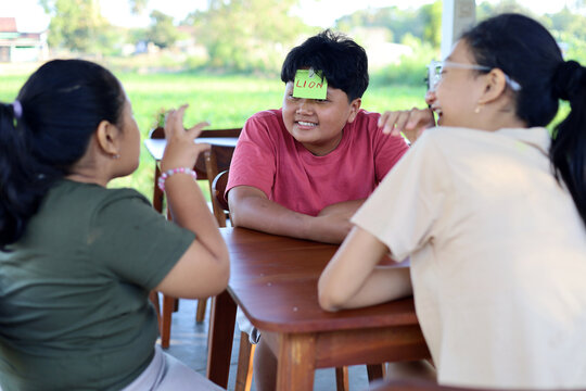Children play the guessing game "Who am I?", with paper stickers on their foreheads.