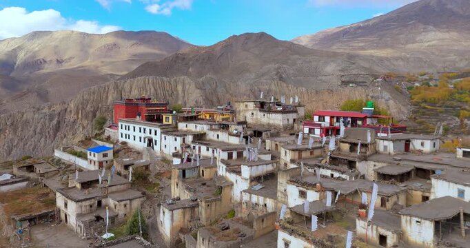Annapurna Circuit, Mustang, Nepal, aerial drone shot of the stone houses and red monastery of Jharkot village set against an arid desert valley and distant snow-capped peaks.