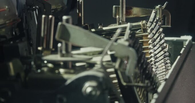 Close-up of a mechanical typewriter experiencing a typebar jam before the operator gently frees the mechanism, illustrating maintenance and analogue office technology.
