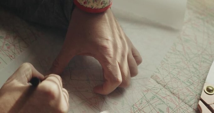 Close-up of a professional fashion designer drafting a dressmaking pattern, illustrating garment development, creative planning and apparel production.