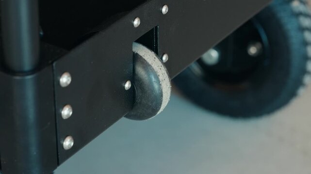 Extreme close-up shot of a black rubber wheel on an industrial cart showing tread detail, dirt, and signs of regular use