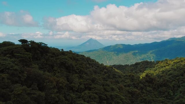 Aerial view of lush mountain forest with clouds and Arenal volcano in Costa Rica