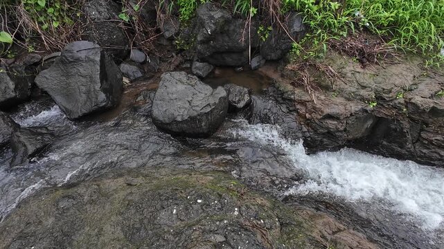 Fast Flowing Rainwater Stream Cascading Over Dark Boulders with Natural Sound