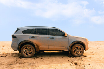 Muddy 4x4 SUV side view parked on a dry dirt field after an off-road adventure. © Emma Grace