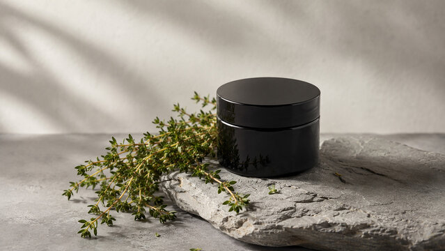 Black Cosmetic Jar with Fresh Thyme on Slate Stone
