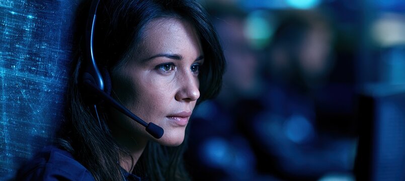 Female radio dispatcher monitoring city grid in modern control room