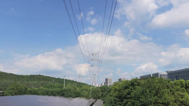 Drone flying forward along solar panels beneath power lines