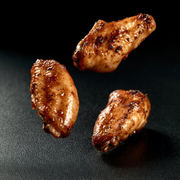 Grilled chicken wing spicy crispy falling black background closeup delicious roasted food