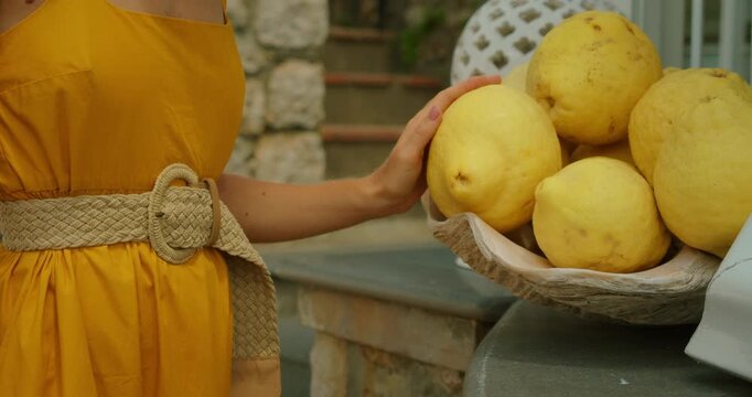 Woman admiring huge freshly picked lemons on rustic outdoor terrace in summer Italy