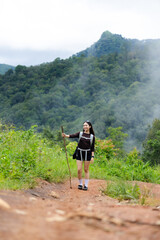 Fototapeta premium Mountain hiker female traveler forest trail misty mountain green forest hiking woman enjoys scenic nature adventure rugged path surrounded by lush vegetation, woodland, and misty mountain landscape