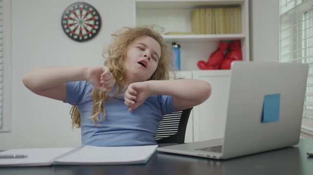 Tired school child using laptop for study. Tired child upset by school. Tired school kid studying at home. Tired student during schooling. Bored student studying. School child bored and frustrated.