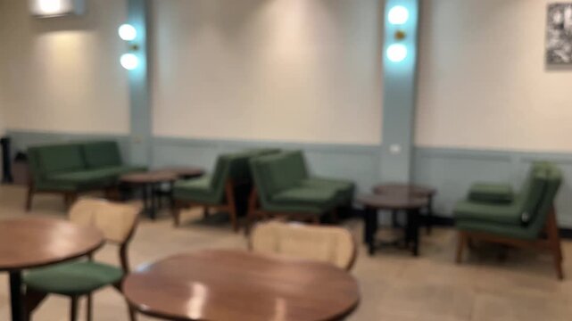 Blurred of interior cafe or coffee shop. empty wooden tables And chairs,  indoor seating. restaurant. interior. green, nature, wall, lamps, lights, warm. night. dine in, dining. work from cafe. brown.