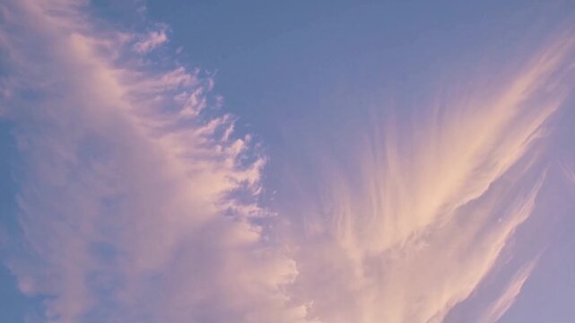 Atmospheric view of soft delicate pink clouds spreading across clear evening sky during serene sunset, peaceful colorful twilight atmosphere over open horizon with beautiful feathery cloud formation