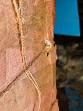 Detailed view of pink paper packaging wrapped with jute twine, showing tape and a small hole