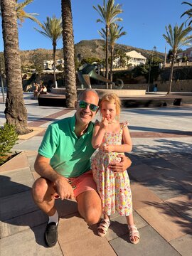 P&egrave;re et petite fille posant ensemble dans un resort bord&eacute; de palmiers
