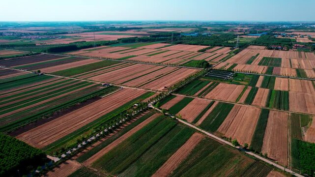 A high-angle aerial shot of patchwork agricultural fields in a rural area, showing diverse cropland and landscape.