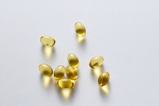 Golden softgel capsules with fish oil supplements on light background
