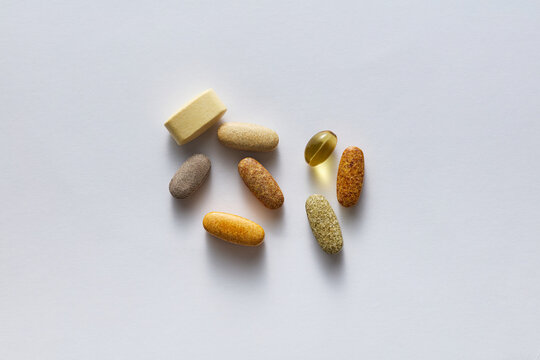 Assorted Vitamin Pills and Herbal Supplement Capsules on White Background
