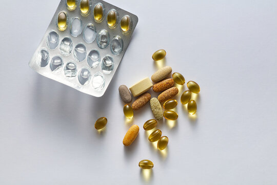 Assorted vitamin pills, gel capsules, and blister pack on white background