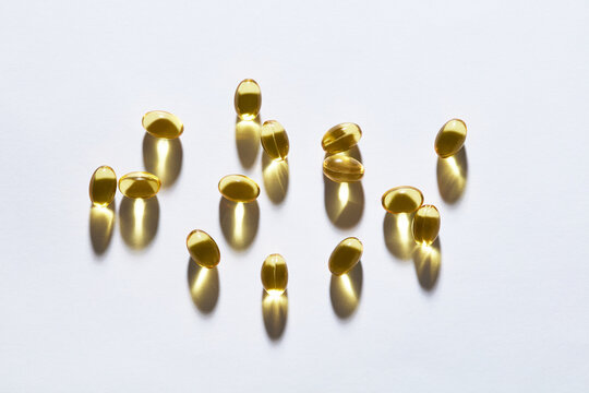 Golden Fish Oil and Omega 3 Softgel Capsules on White Background