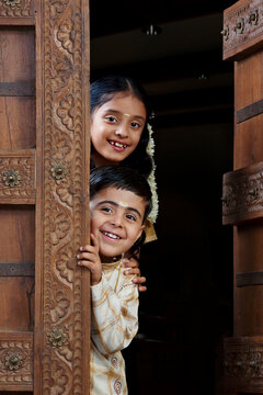 South Indian boy and girl peeping from the doorway 