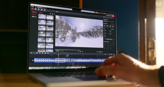 Close-up view of hand using trackpad to edit video timeline on laptop computer display screen in studio