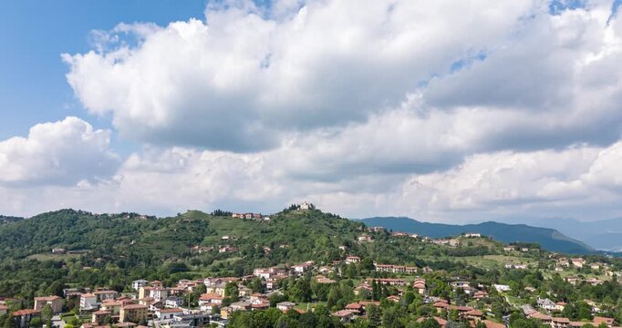 Montevecchia hilltop village and surrounding countryside shift under moving clouds in a fast aerial hyperlapse.