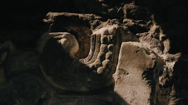 Detailed close-up shot of an ancient Mayan stone carving at Temple of the Great Jaguar, Tikal. Dramatic lighting enhances weathered textures in this iconic Guatemalan archaeological treasure.