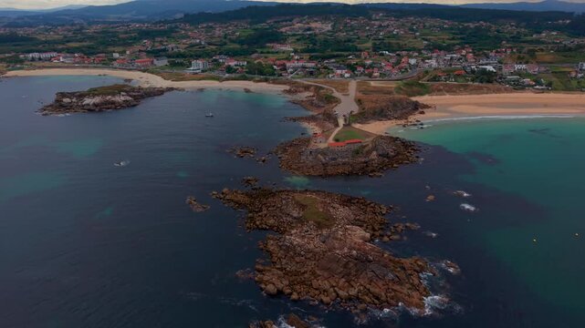 Aerial drone view of the Nossa Senhora da Lanzada rocky headland with its chapel sandy beaches and turquoise water on the Galicia coast in Spain