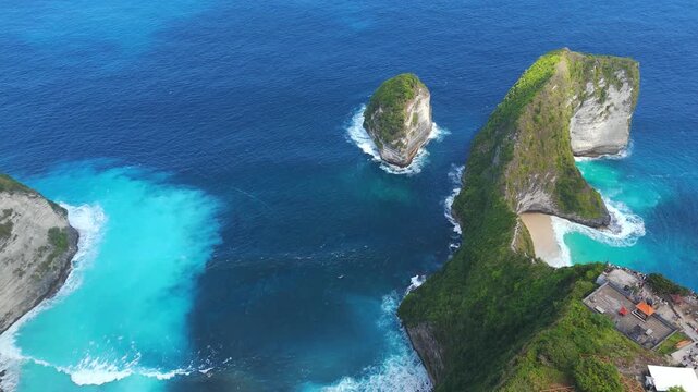 Kelingking Beach and its famous T Rex cliff rise above turquoise coves in a smooth aerial pan.