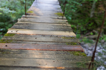 Fototapeta premium Wooden suspension footbridge close-up of weathered planks and rope walkway for outdoor banner or background design