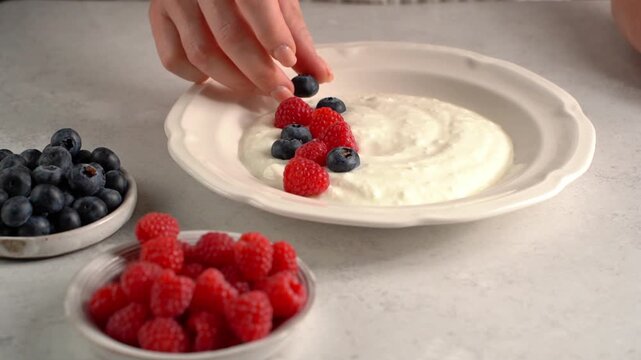 Decorating yogurt with raspberries and blueberries
