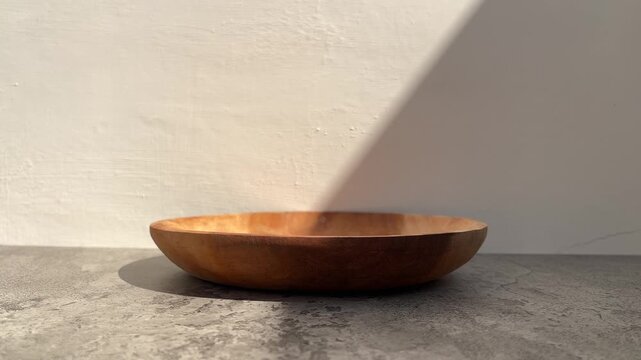 side view of empty wooden plate with shadows. gray cement table. white wall. copy space, empty, free, negative, text, design. black, dark. line, lines. sunlight, sunrise, sunshine. product. close up. 