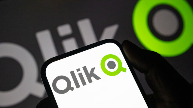 Qlik data analytics software logo on mobile phone screen held against company brand background.