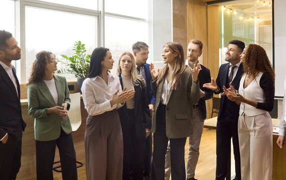 Business team colleagues in meeting office discussion. A confident leader gives presentation while coworkers share applause supporting collaboration in a workspace. Teamwork leadership concept.