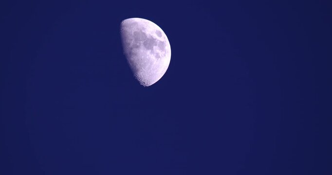 Half moon glowing against a clear deep blue sky