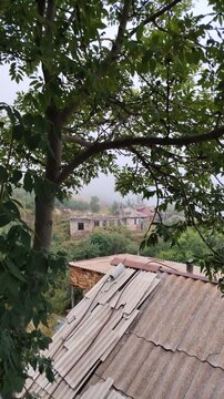 Thick fog and clouds rolling over a mountain village and forest. Beautiful view of the mountains in the morning. Fog covered the houses of the village. Green forests and fields and white fog.
