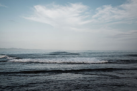 Moody coastal seascape with gentle waves, overcast sky and distant horizon, soft muted tones and textured ocean surface