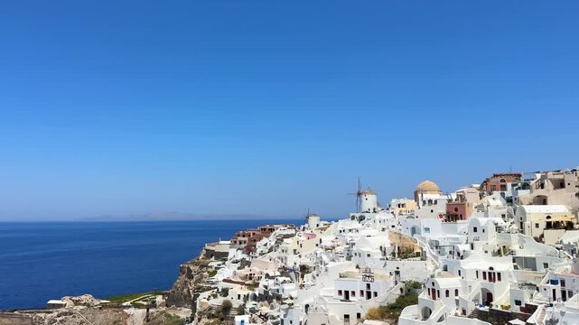Santorini island, Greece. White cycladic architecture and famous windmills in Oia town. Blue sea and the blue sky at sunny day. Panoramic view. Travel and summer vacation concept
