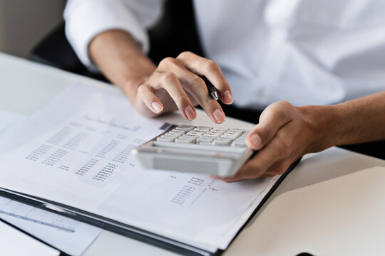 Office administrator reviewing audit documents on table with calculator and financial file folders