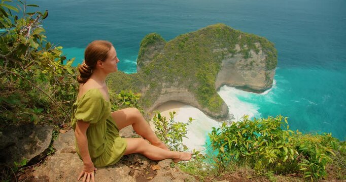 Calm travel moment as woman overlooking turquoise bay and cliffs in Nusa Penida Bali