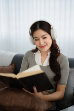 Woman sitting in living room to enjoying time with listening the music and reading a book in home