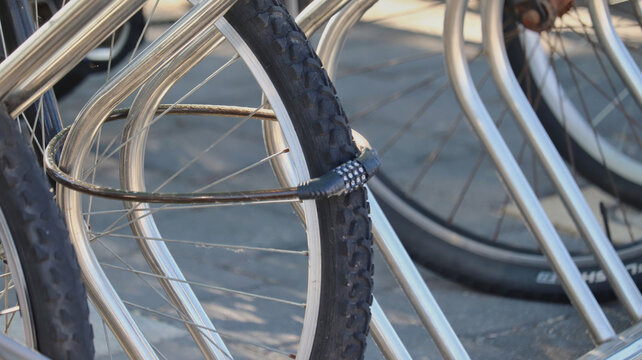 Bicycle Wheel Secured with Combination Lock to Metal Bike Rack in Urban Setting
