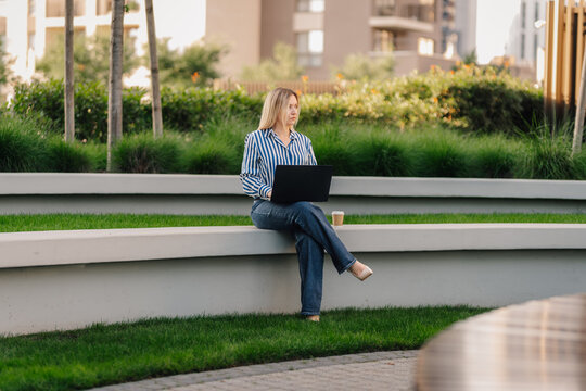 Woman working remotely using laptop in urban park